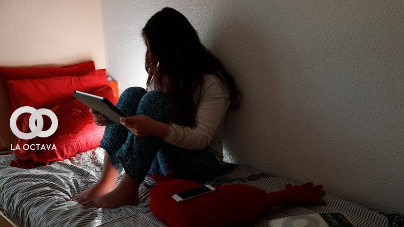 Una adolescente, en su habitación, consulta los mensajes en dispositivos móviles en Madrid